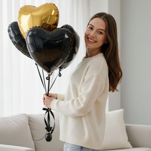 1 Golden & 2 Black Heart-Shaped Helium Foil Balloons Set held by a model, view 1