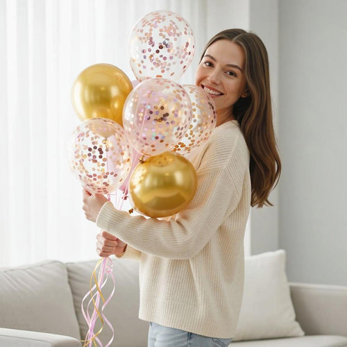 2 Golden Foil Balloons with 5 Pink Confetti Balloons held by a model, view 1