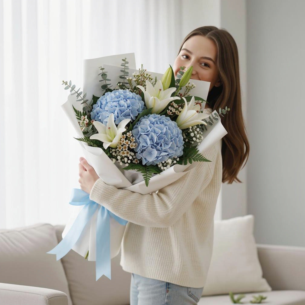 Elegant Bouquet of Blue Hydrangea & White Lilies for Father’s Day held by a model, view 1