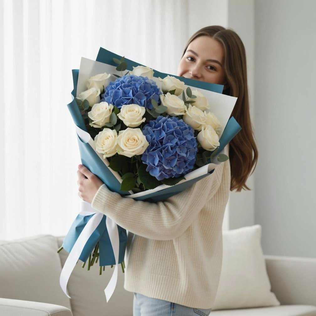 Teacher’s Day Royal Blue Hydrangea & White Rose Bouquet held by a model, view 1